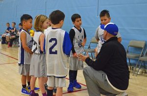 youth basketball coach leaning down in huddle during a timeout