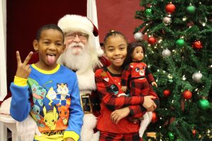 2 children in pajamas sitting and smiling on Santa's lap