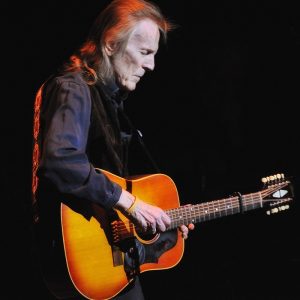 Gordon Lightfoot facing right with a sunburst acoustic guitar