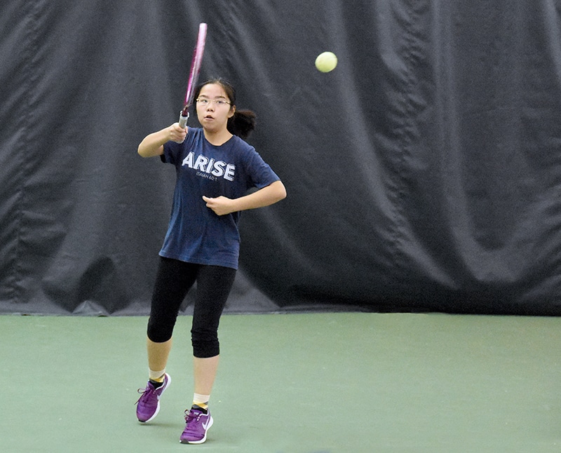 Young female tennis player following through with her swing after hitting a tennis ball