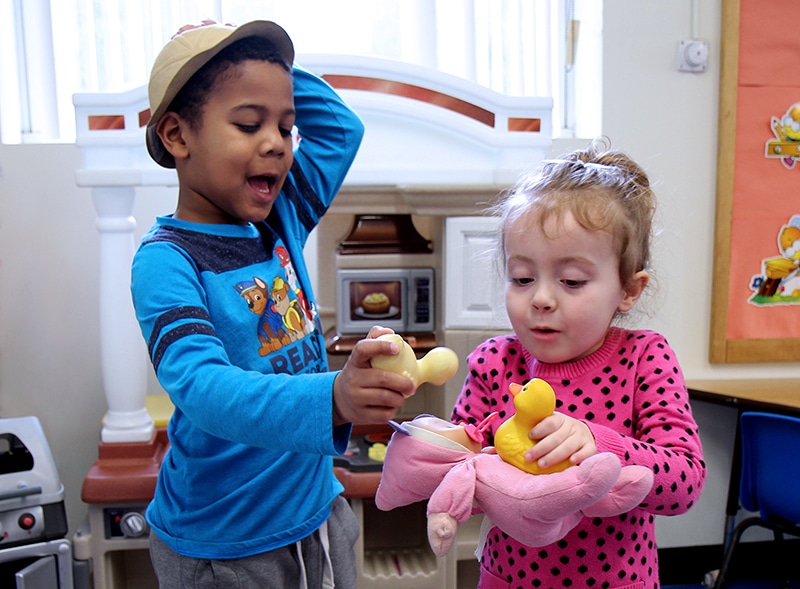 a young boy and young girl playing pretend with rubber duckies and a baby doll