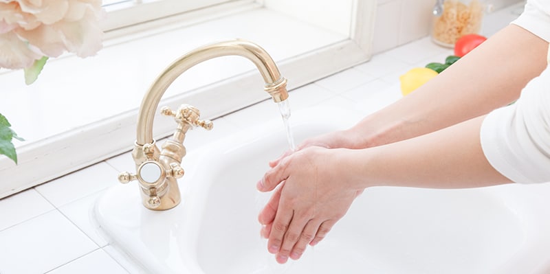 Hand washing sink in the hands of a woman by the window