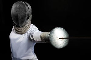 Portrait of fencer woman wearing white fencing costume. Isolated on black background.