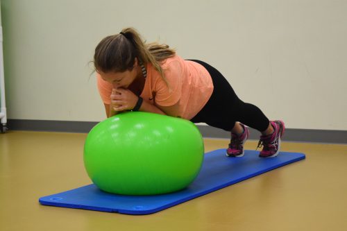 A person doing a plank on a green exercise ball.