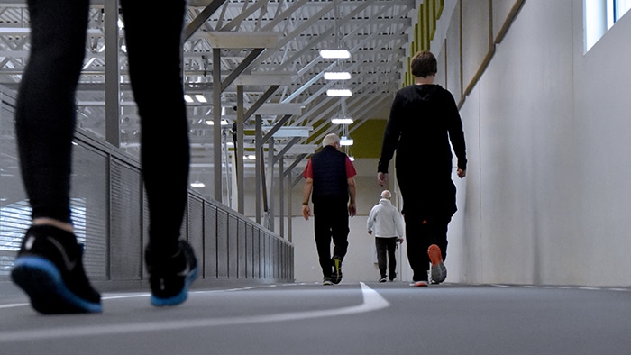 Ground view of 4 staggered patrons walking the Leonhard Recreation Center Indoor Walking Track.