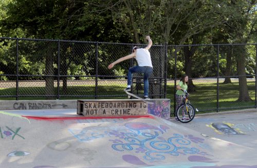 A skateboarder grinds on a rail at a skatepark.