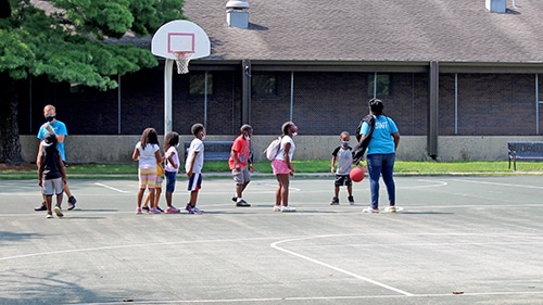 Champaign Park District staff are playing a game of basketball with kiddos.