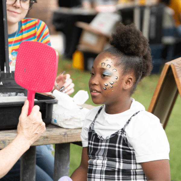 A young child gets their face painted