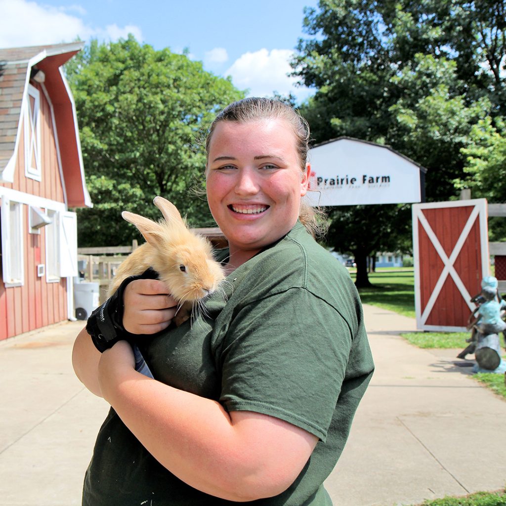 Prairie Farm staff member holding a bunny and smiling.
