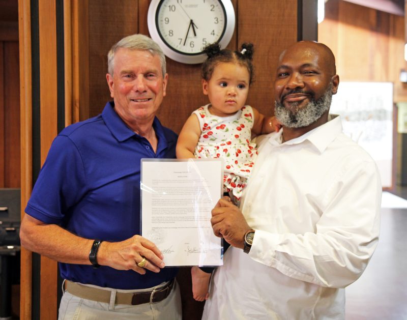 Jameel Jones and CPD Commissioner Craig Hays smiling holding the Champaign Park District Resolution.