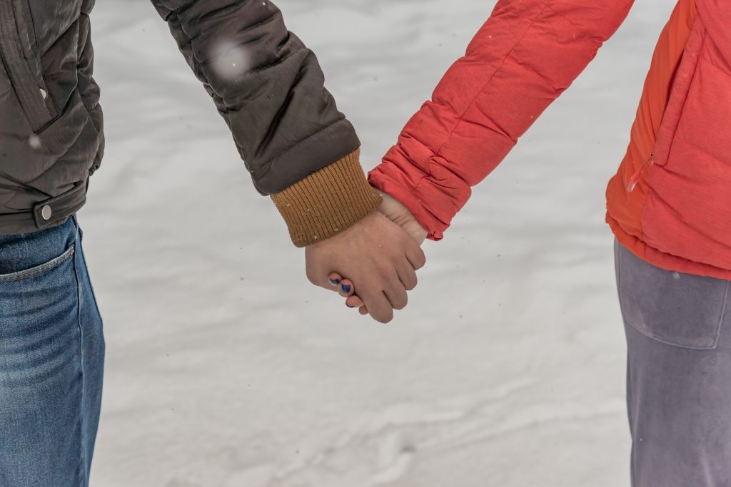 Man and woman holding hands. Young couple walking on winter park