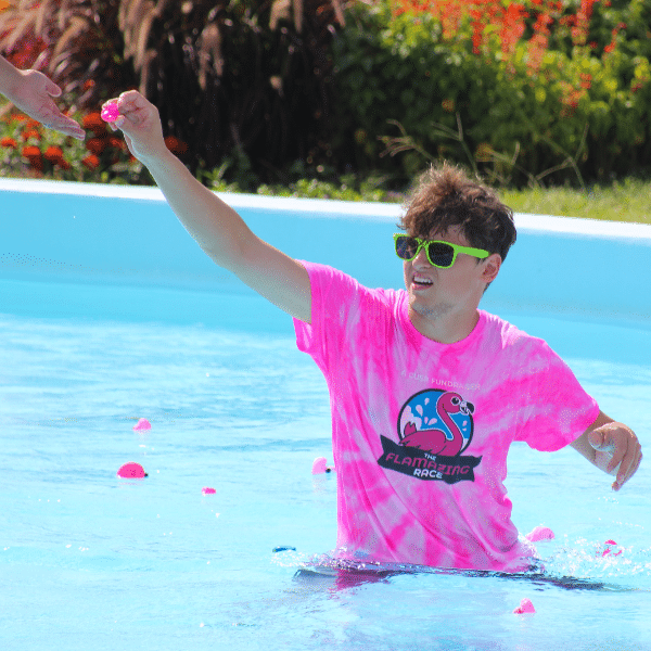 A man holds a rubber flamingo in a pool