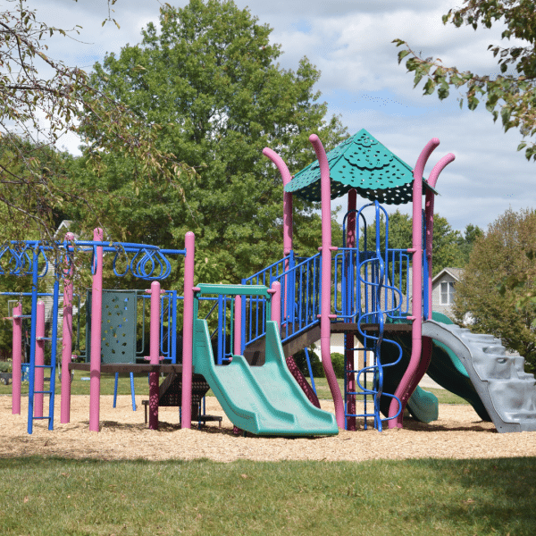 A playground with a double slide and platforms to climb on