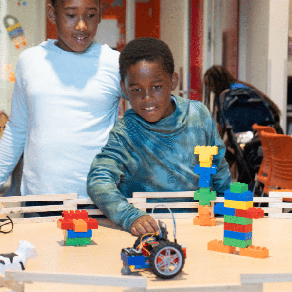 Two children build a car course with Legos