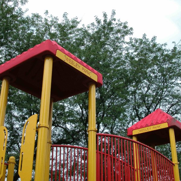 Wesley Park Playground, featuring yellow and red towers connected by a red bridge.