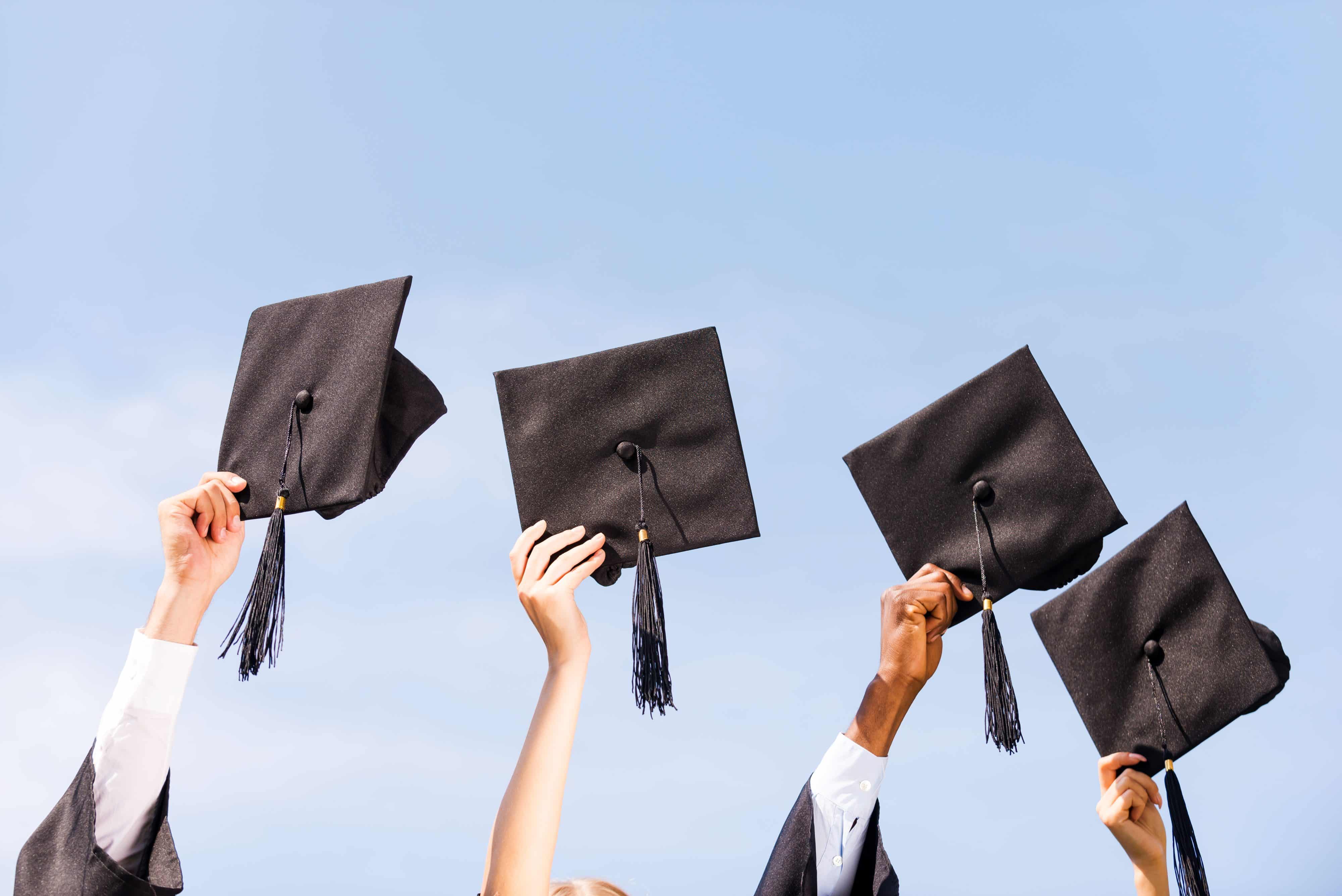 Hands holding graduation caps