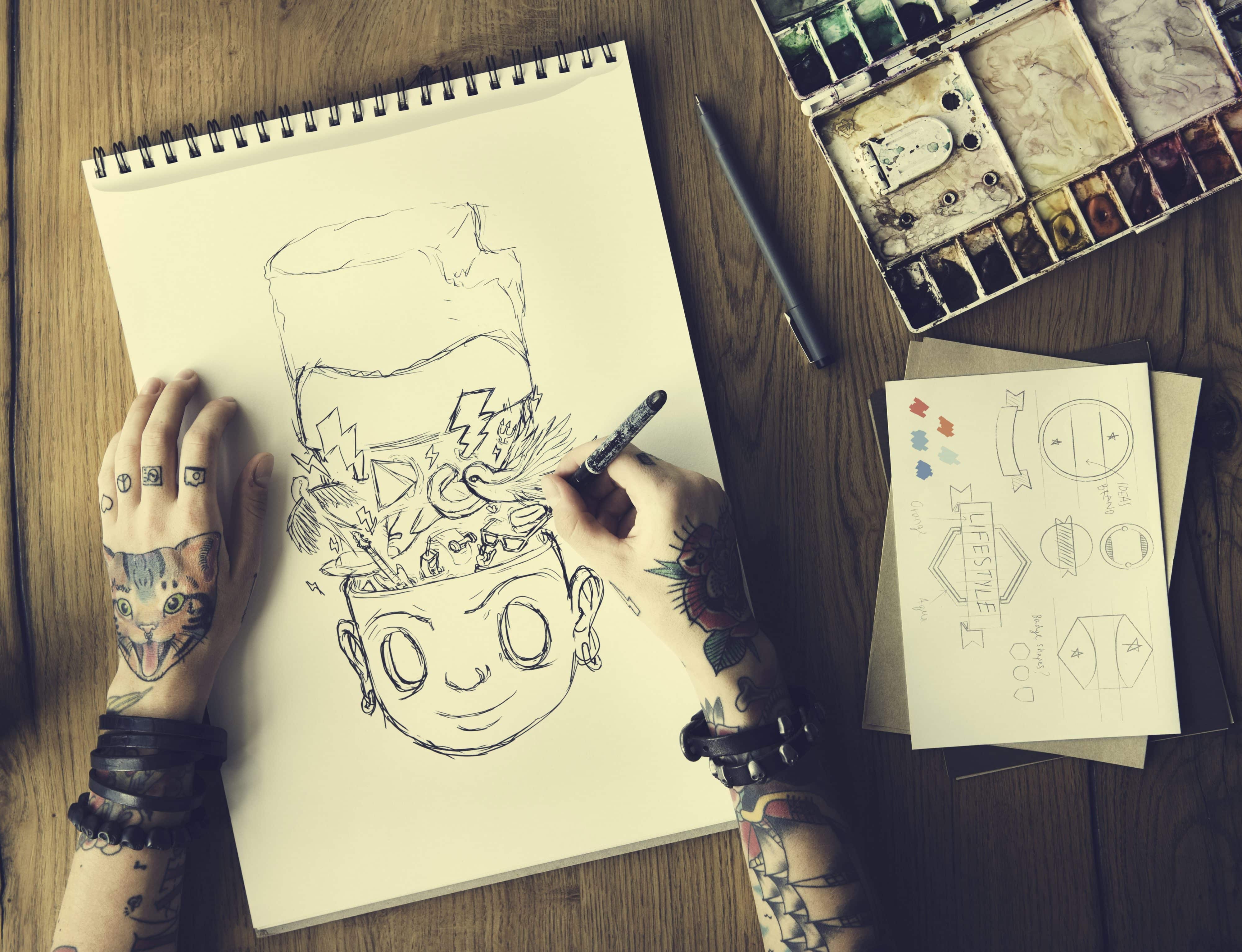 Tattooed hands drawing a comic