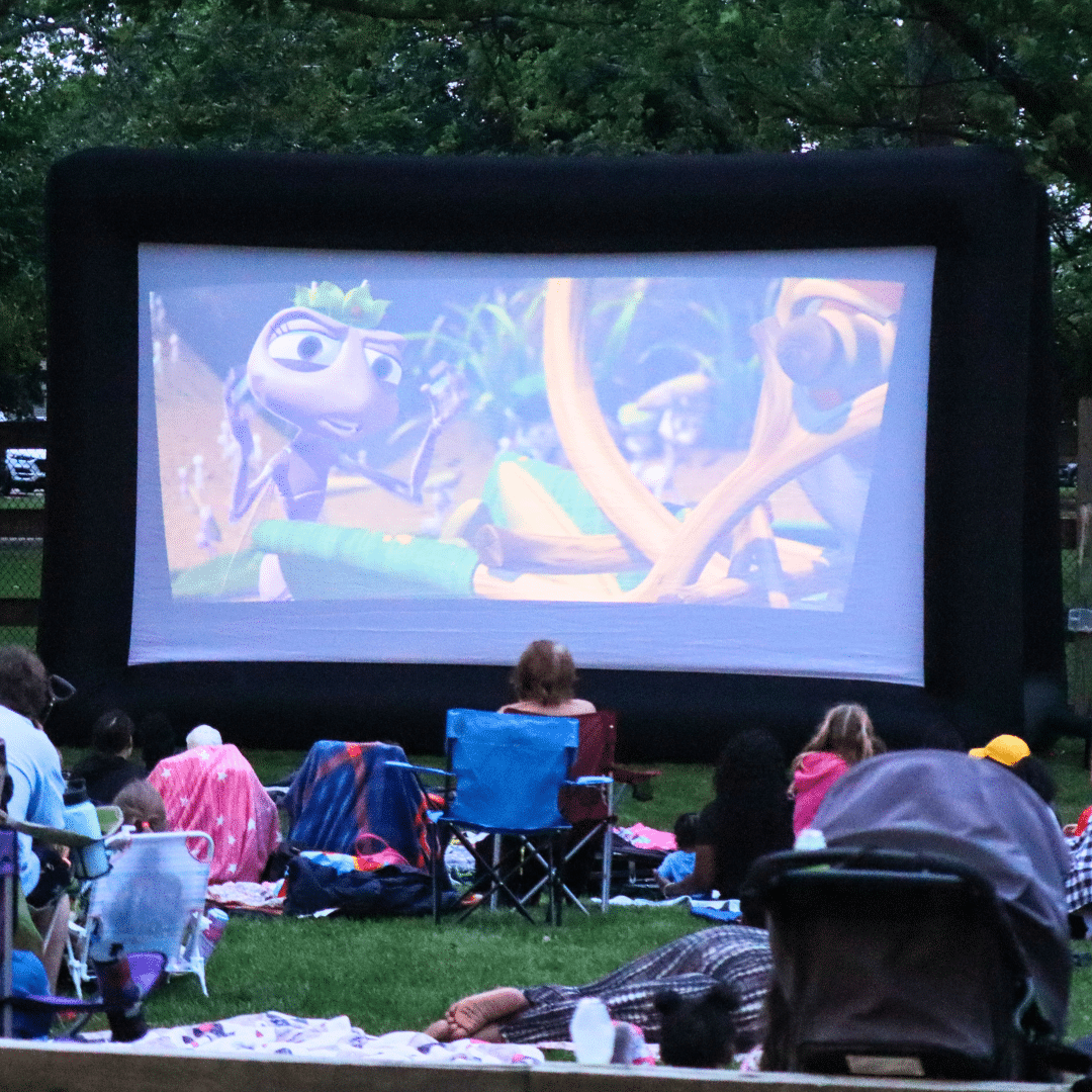 People sitting on the lawn watching a movie on a projector