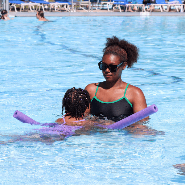 A young woman teaches a girl to swim.