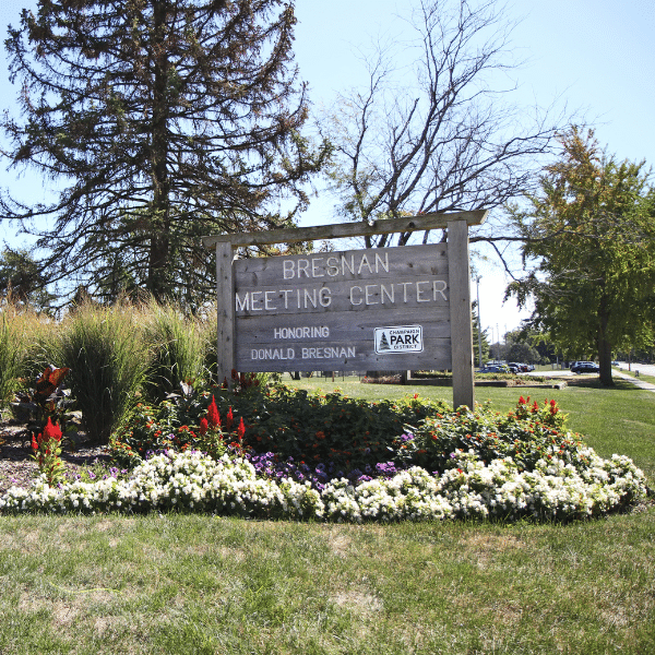 A large wooden sign sits in a color flower bed. The sign says, "Bresnan Meeting Center."