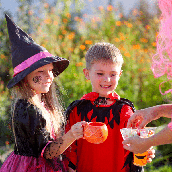 Two small children wear costumes and trick or treat.